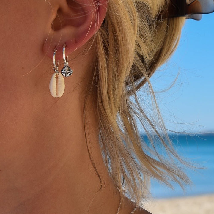 Sterling silver seashell hoop earrings styled with cowrie shell hoops