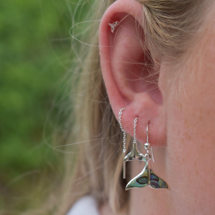 Whale tail hook earrings with pāua shell inlay worn on model, sterling silver ocean jewellery