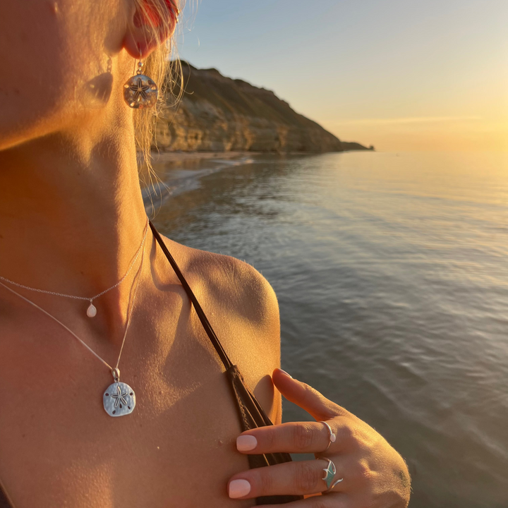 Sand dollar pendant necklace worn as part of an everyday ocean-inspired jewellery look