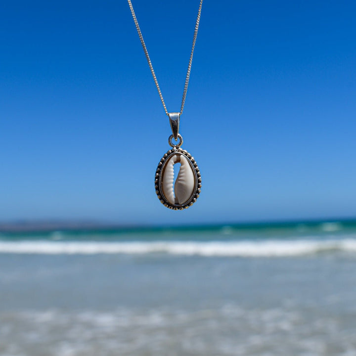 cowrie shell necklace in sterling silver with a blue ocean background