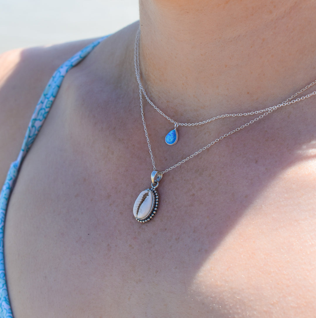 Sterling silver cowrie shell necklace worn with casual coastal outfit, side profile view