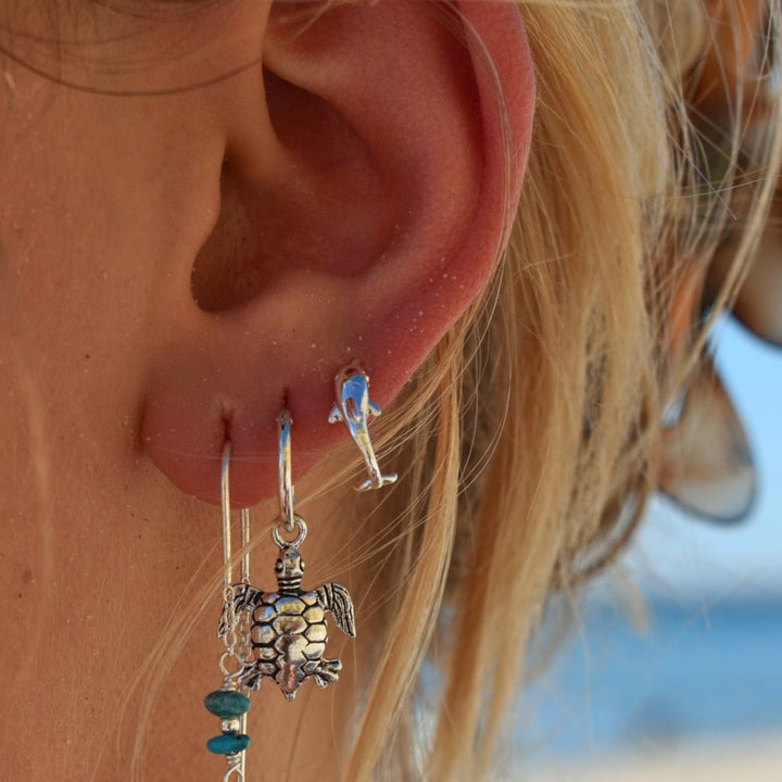 Ocean-inspired dolphin stud earrings worn as part of a coastal jewellery look