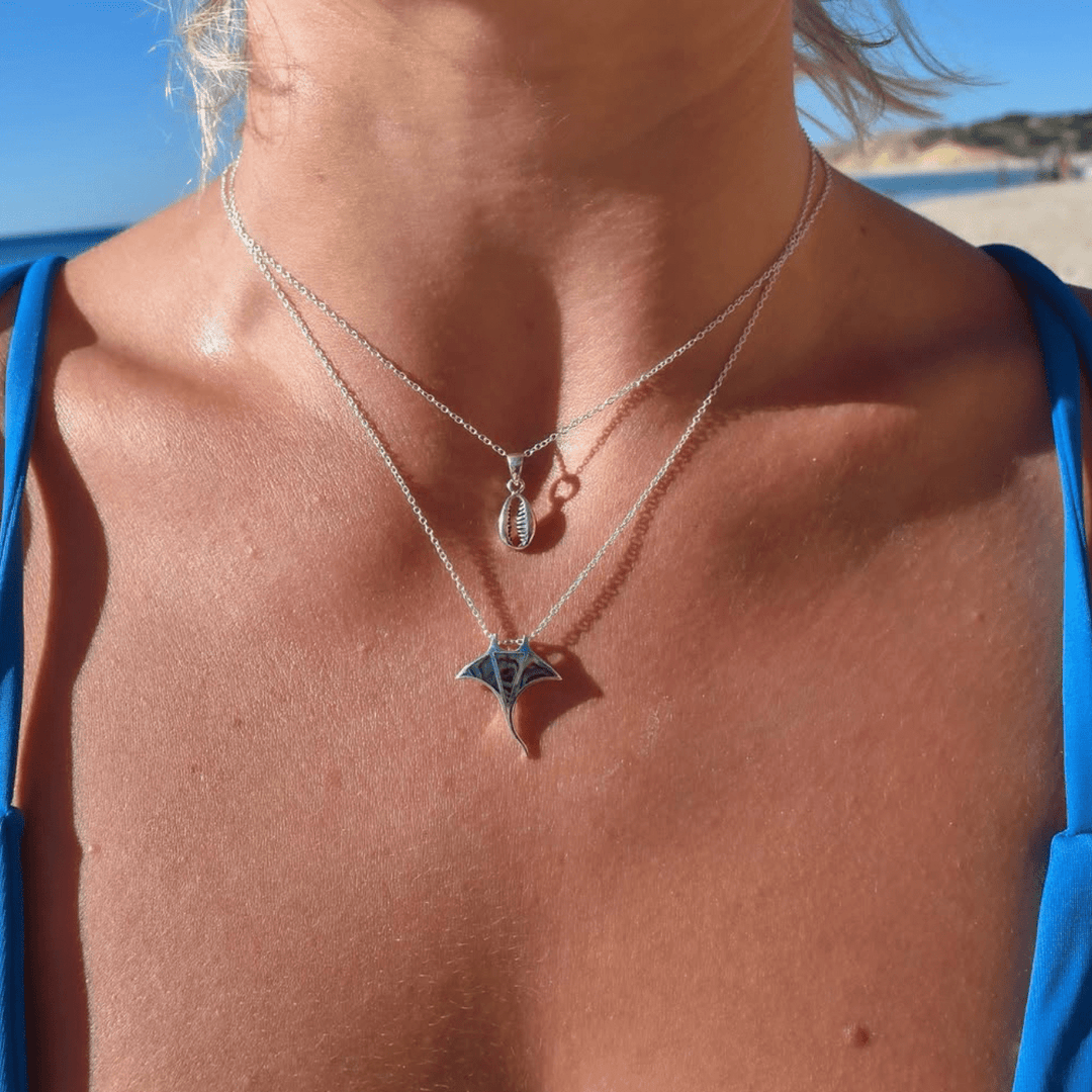 Paua shell manta ray pendant necklace styled with silver layers, worn close to the neck