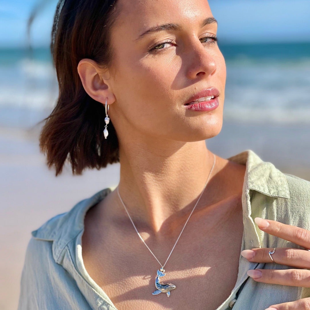 Model smiling in the sun wearing sterling silver pearl hoop earrings