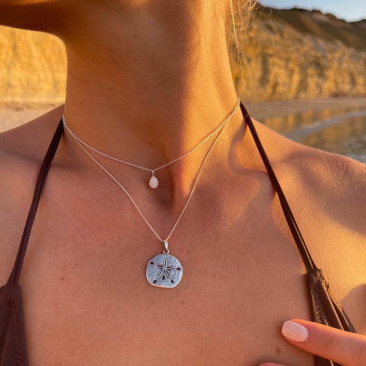Sterling silver sand dollar necklace worn layered with other beachy jewellery