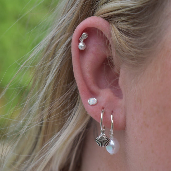 Sterling silver seashell hoop earrings styled with layered coastal accessories