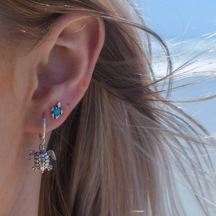 Blue opal turtle stud earrings in sterling silver worn on ears, ocean-inspired design