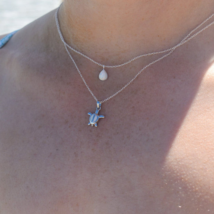 Lab-grown white opal pear necklace worn close to the neck, sterling silver setting