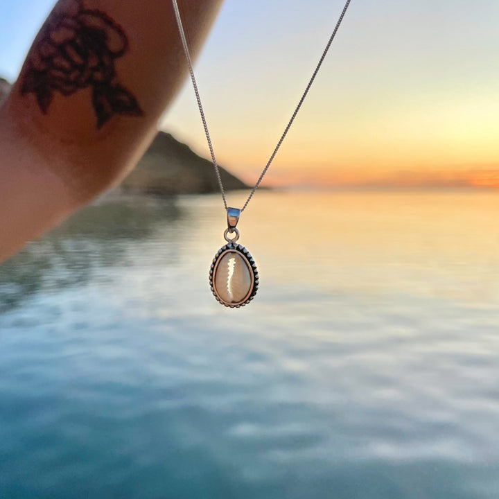 Ocean-themed sterling silver cowrie shell necklace styled with layered beach jewellery