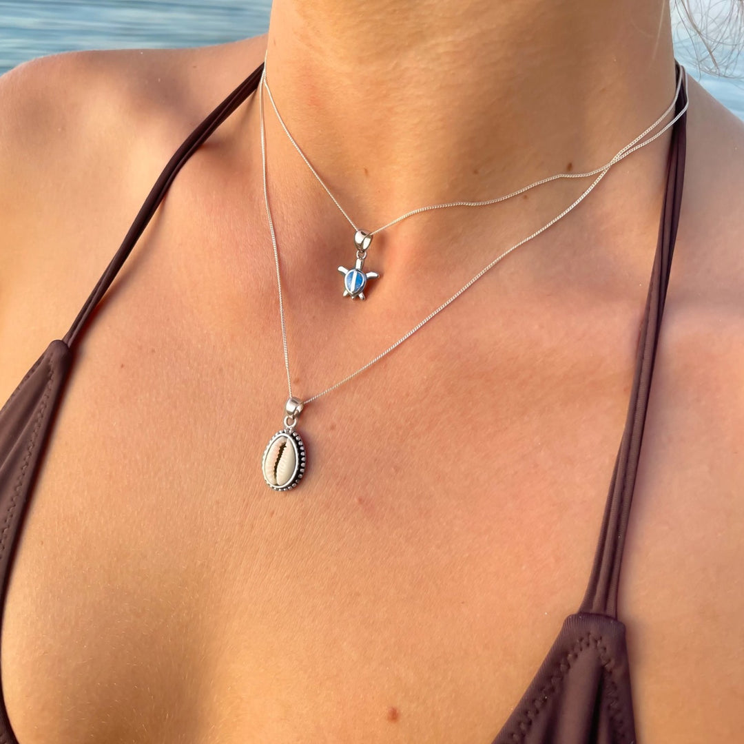 Cowrie shell pendant necklace worn close to the neck, sterling silver coastal jewellery